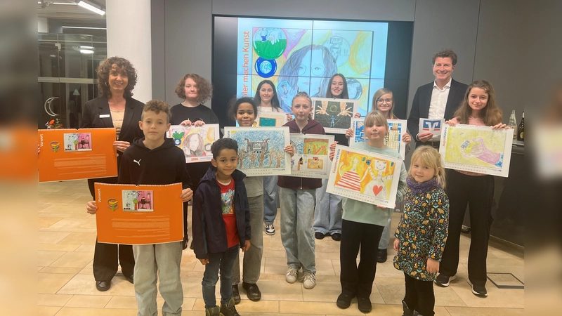 Stolz präsentieren die Kinder und Jugendlichen den Kalender 2026 „Schüler machen Kunst“ zusammen mit Bankvorstand Klaus Berger (r.) und Marketingreferentin Michaela Steiner (l.). (Foto: VR Bank Dachau)