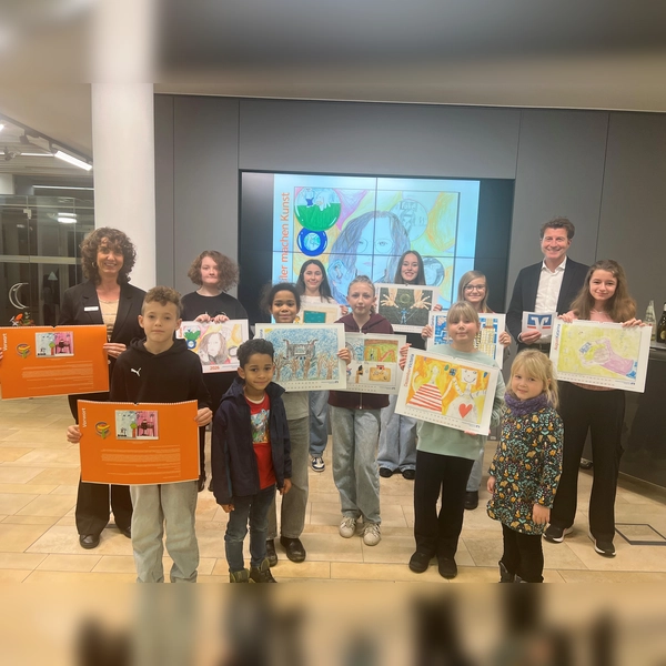 Stolz präsentieren die Kinder und Jugendlichen den Kalender 2026 „Schüler machen Kunst“ zusammen mit Bankvorstand Klaus Berger (r.) und Marketingreferentin Michaela Steiner (l.). (Foto: VR Bank Dachau)