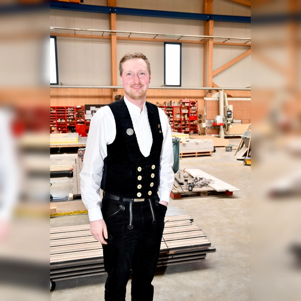 Der stellvertretende Innungsobermeister Benedikt Lachner in der traditionellen Zimmerer-Kluft in der Produktionshalle seines Betriebs. (Foto: Riffert/JOB 2026)