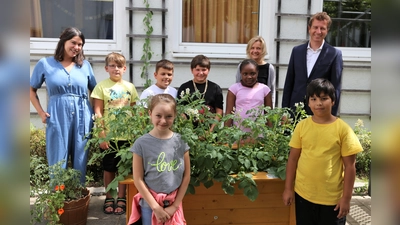 Ganztagspädagogin Marion Reiss (li), Schulleiterin Viktoria Ledermann und Bankvorstand Klaus Berger mit den Kindern der Greta-Fischer-Schule vor einem der beiden Hochbeete.  (Foto: VR Bank Dachau)