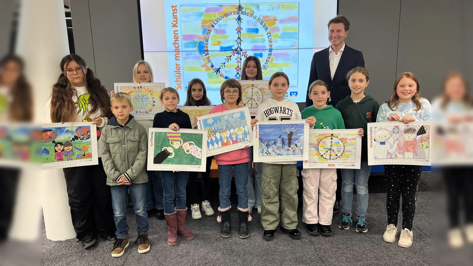 Stolz präsentieren die Kinder und Jugendlichen den Jugendmalkalender 2024, hinten Bankvorstand Klaus Berger. (Foto: VR-Bank)