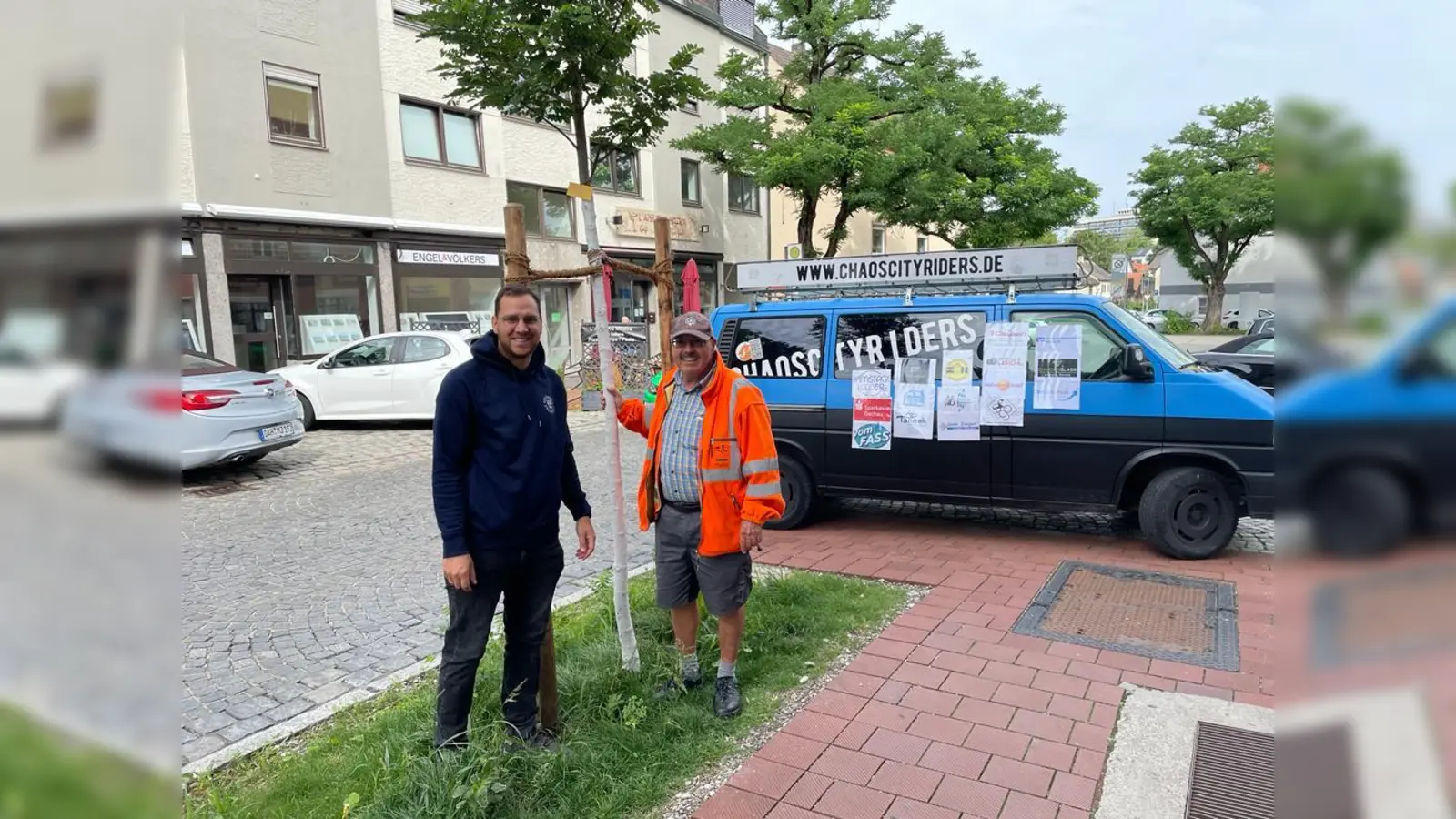 Frank Großhans (re) vom Stadtgrün mit Chaoscityrider-Vorsitzendem Bernard Zeidler und dem neuen Baum in der Augsburgerstraße. (Foto: Chaoscityriders)