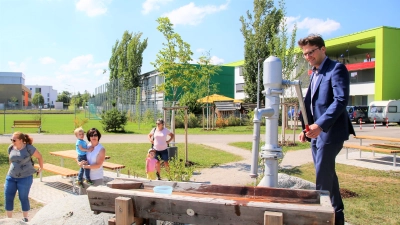 OB Florian Hartmann an der Wasserpumpe auf dem neuen Spielplatz. (Foto: Stadt Dachau)