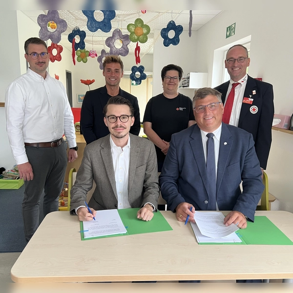 Dennis Behrendt und Stefan Löwl unterzeichnen den Vertrag. Im Hintergrund: Dominik Ulbrich, Michael Schäfer,Larissa Friedl und Bernhard Seidenath. (Foto: BRK Kreisverband Dachau)