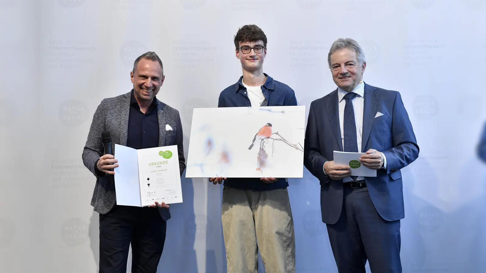 Ein Gimpelmännchen fotografierte Moritz Winkler (Mitte) und kam damit auf Platz 3 in der Kategorie „Magie der Farben” (AK3: 15-18 Jahre). Umweltminister Thorsten Glauber (links) und Michael Apel (Leiter des Museums Mensch und Natur) gratulierten. (Foto: Marcus Schlaf)