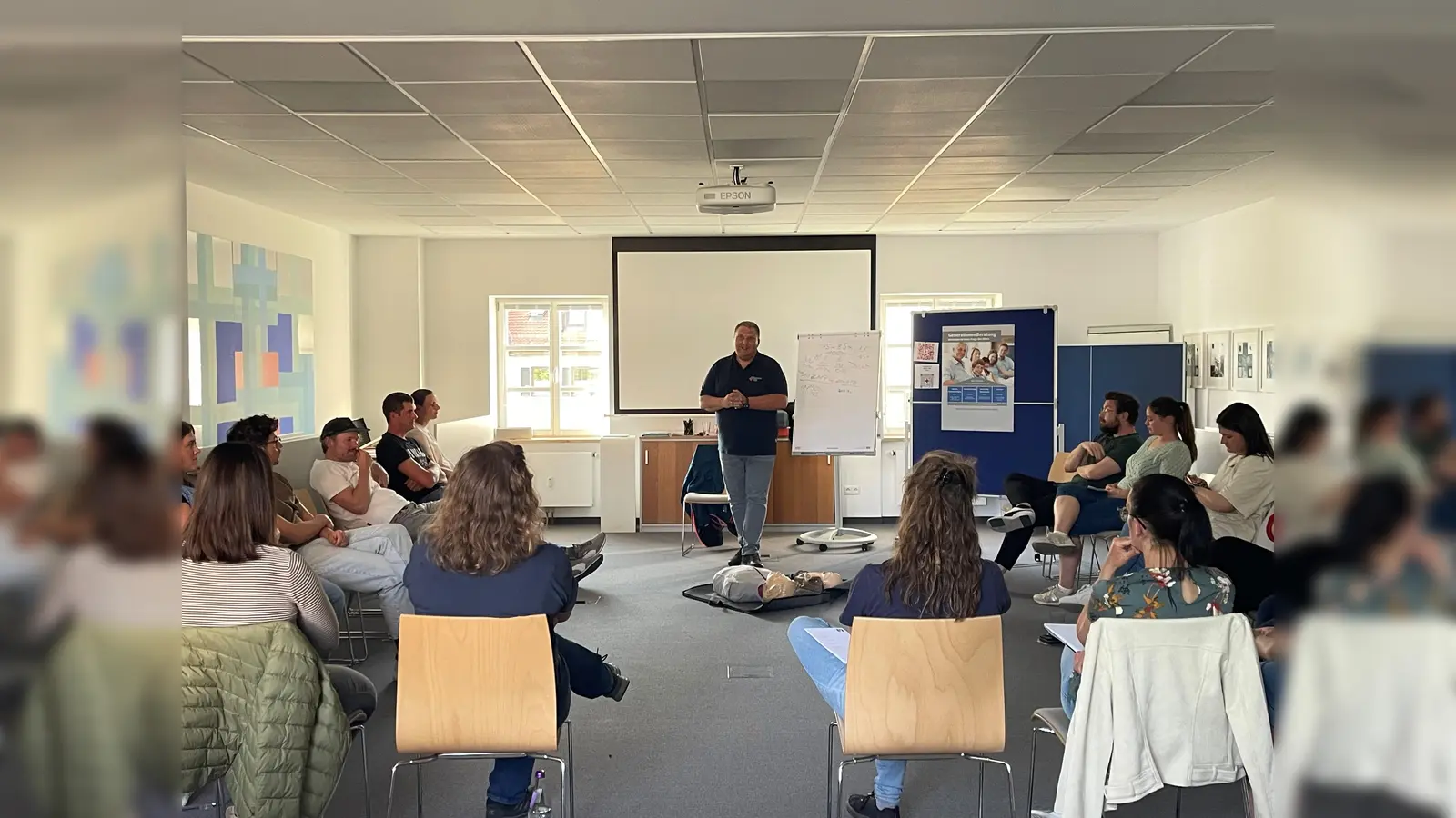 Ausbilder Michael Karlstetter demonstriert den jungen Eltern, wie man schnell und sicher Erste Hilfe leistet. (Foto: VR Bank Dachau)