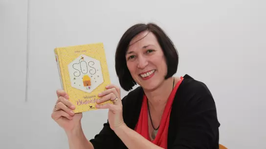 Kinderbuchautorin Esther Kuhn mit ihrem Buch „SOS – Mission Blütenstaub“. (Foto: Stadtbücherei)