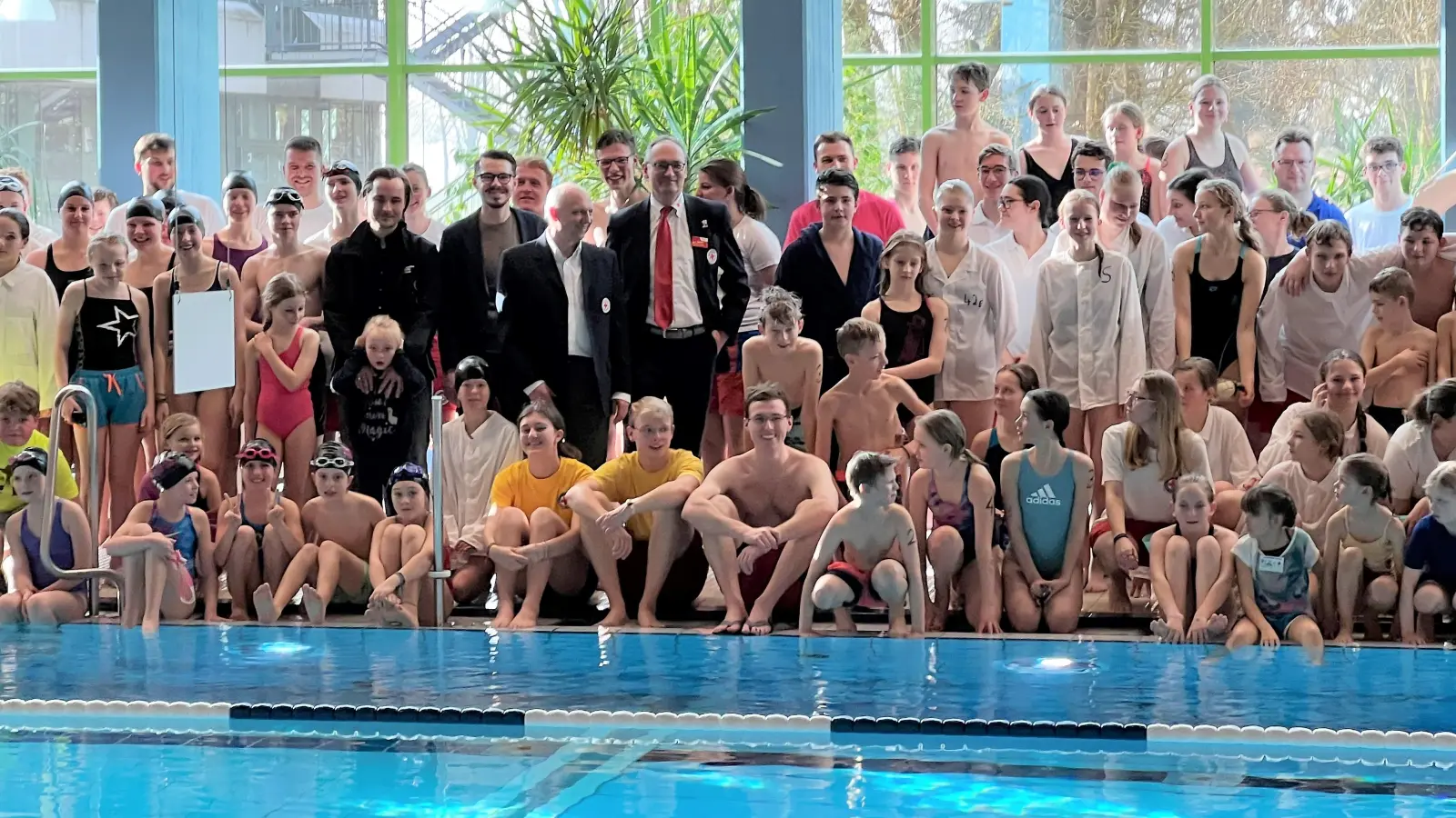 Max Frisch, Dennis Behrendt, Jörg Westermair und Bernhard Seidenath (von li) umringt von den Schwimmerinnen und Schwimmern vor dem Wettkampf. (Foto: BRK Dachau)