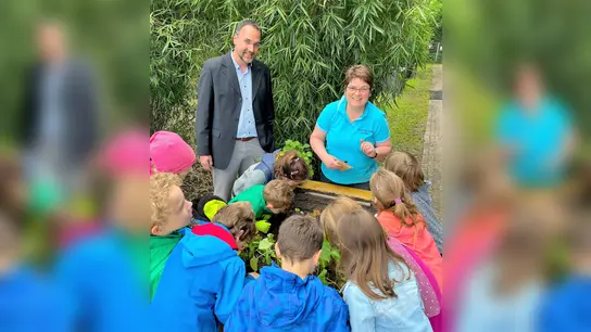 Ulrich Zeiler, VR Bank Dachau, und Birgitt Heermann mit den Kindern am Hochbeet. (Foto: VR-Bank)