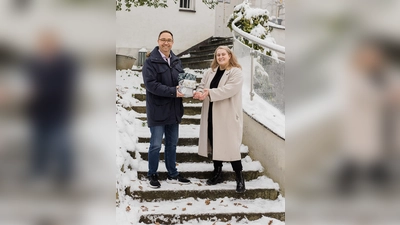 Ulf Tausche, Vorsitzender des Montessori Vereins Dachau, übergab die Weihnachtsgeschenke im Hof des Kinderhauses an Laura Kaufmann, Leiterin des AWO-Frauenhauses in Dachau. (Foto: red)
