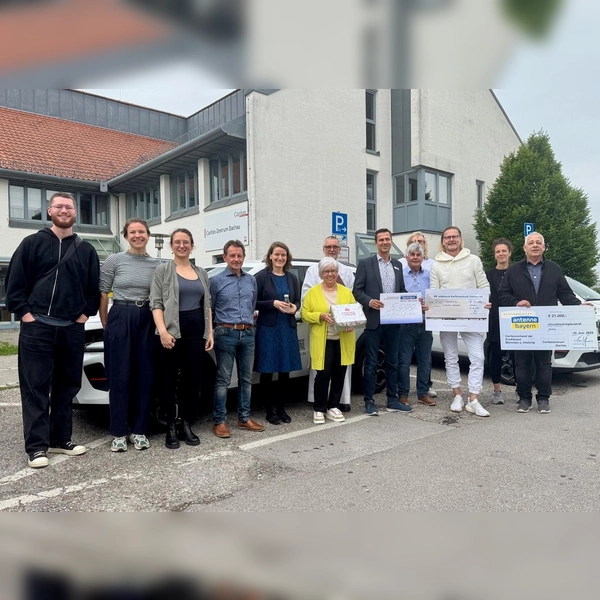 Holger John, Stephanie Wollrab (Stiftung Antenne Bayern), Frank Menauer, Günther Rauch (Löwenkinder e.V.), Anton Limmer (im Hintergrund), Jürgen Vogt (Sparda Bank), Diakon Raimund Richter, Dagmar Krumpach (Sparkasse Dachau), Heidi Schaitl, Andreas Miller, Paola Palmieri, Kathi Köstler, Tom Deschler (alle Caritas-Zentrum Dachau) vor den drei weißen Elektroautos (von rechts). (Foto: Caritas)