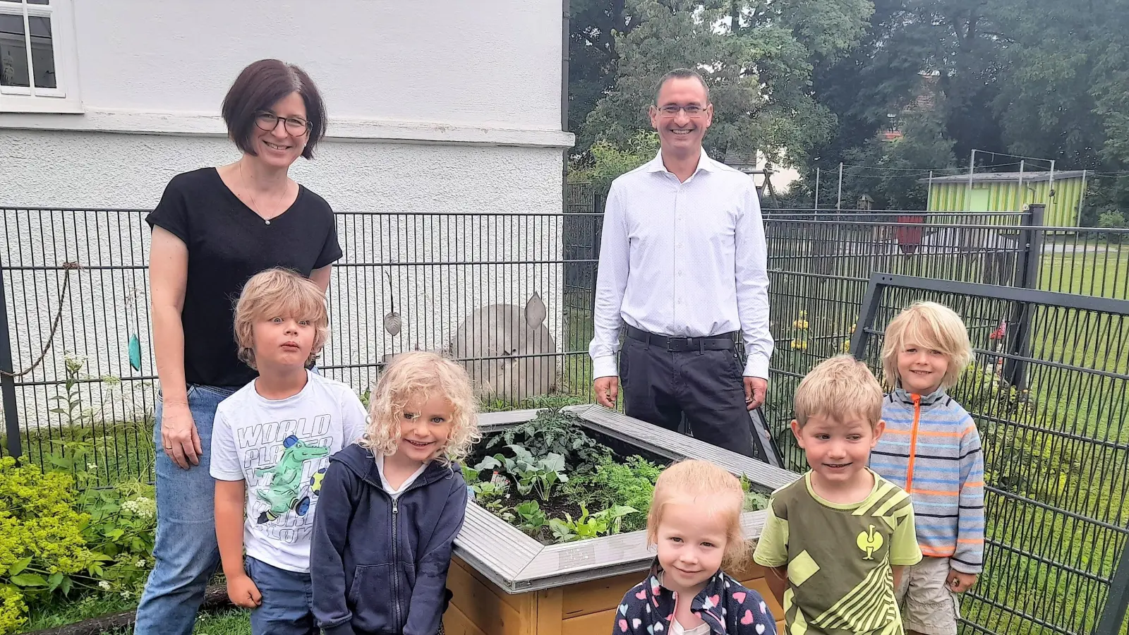 Florian Axtner (VR Bank Dachau) und Kindergartenleiterin Kathrin Czerny mit den Kindern am Hochbeet. (Foto: VR Bank)